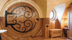 Une porte en bois ornée d’une poignée en métal décorative, un petit banc en bois et une fenêtre ronde.