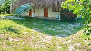 A thatched-roof house with a small porch, surrounded by lush greenery and palm trees. - Santuario Sierra Sagrada (Santa Marta)