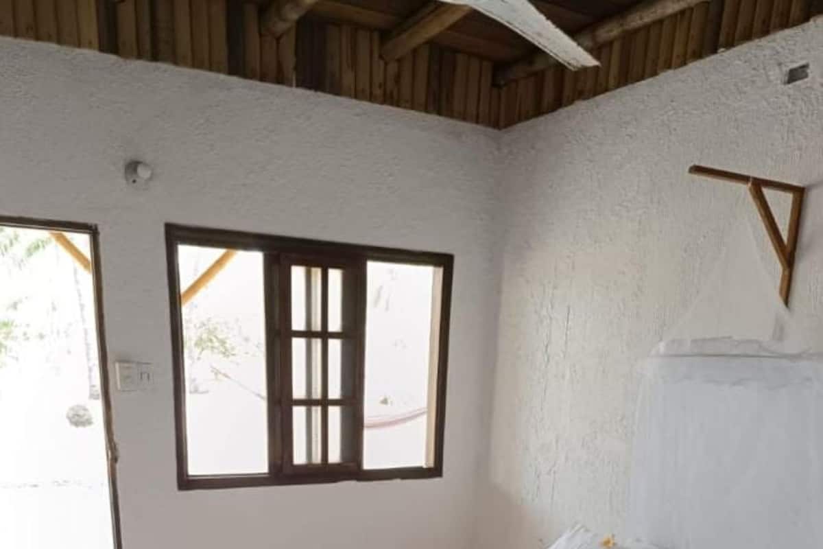A bedroom with a bed, a window, and a wooden ceiling.