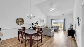 A spacious living area with a dining table, sofas, and a large window offering a view.