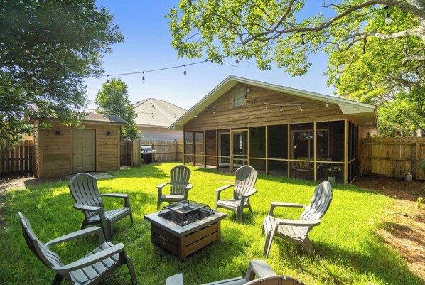 Un jardin avec un patio couvert, un espace extérieur aménagé avec des fauteuils Adirondack, un barbecue et une terrasse en bois.