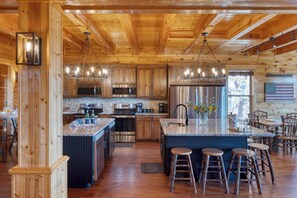 Una cocina amplia con armarios de madera, electrodomésticos de acero inoxidable y una isla central con taburetes.