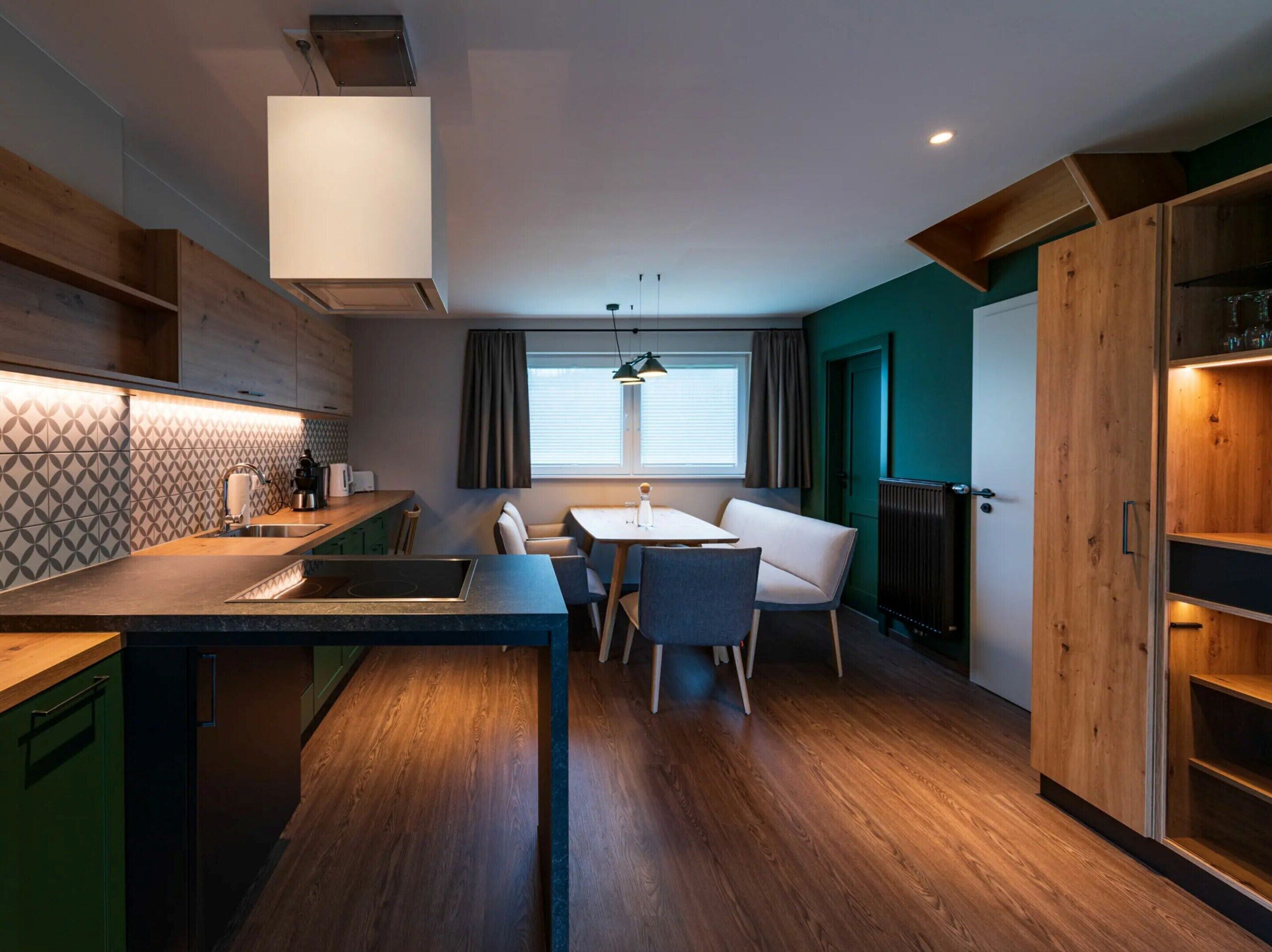 A modern kitchen with a dining area, wooden cabinets, and a built-in oven.