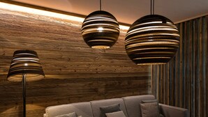 A modern living room with a wooden wall, a grey sofa, and three hanging pendant lights. - Premium Chalet in Buntenbock (Clausthal-Zellerfeld)