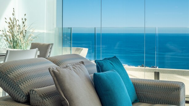 A balcony with a view of the ocean, a sofa with patterned cushions, and a potted plant. - Apartment 'Stupa Hills - Spectacular Sea Views' with Sea View, Wi-Fi and Air Conditioning (Benalmadena)