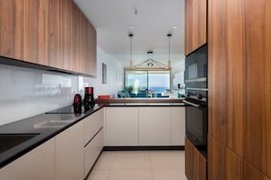 Une cuisine moderne avec des meubles en bois, un plan de travail noir et une vue sur l’espace de vie.