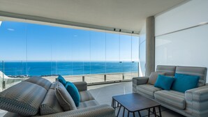 A modern living room with a large glass window overlooking the ocean, furnished with patterned sofas and a coffee table. - Apartment 'Stupa Hills - Spectacular Sea Views' with Sea View, Wi-Fi and Air Conditioning (Benalmadena)
