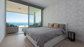 A bedroom with a bed, a small table, a sofa, and a view of the sea. - Apartment 'Stupa Hills - Spectacular Sea Views' with Sea View, Wi-Fi and Air Conditioning (Benalmadena)