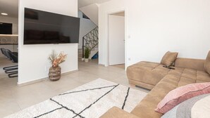 Un moderno salón con un televisor de pantalla plana montado en la pared, un sofá marrón y una alfombra estampada.
