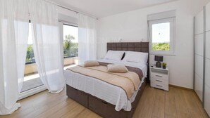 Un dormitorio con una cama grande, una mesita de noche, un armario y una ventana.