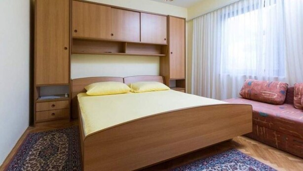 Un dormitorio con cama, armario de madera y sofá.