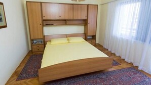 Un dormitorio con cama, armario de madera y lámpara colgante.