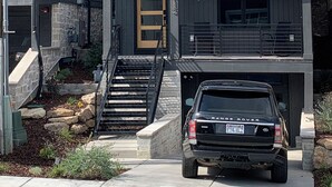 Een modern huis met twee verdiepingen, een zichtbare garage en een geparkeerde Range Rover.