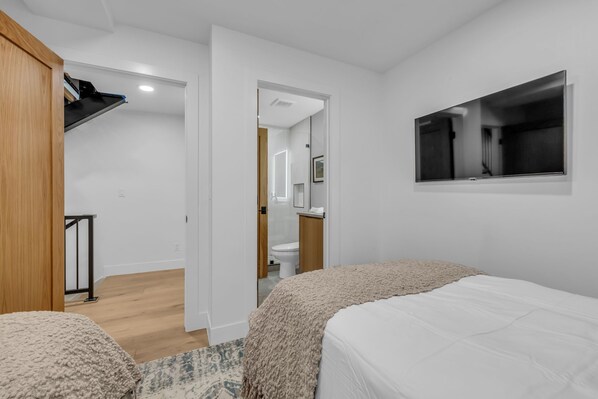 Un dormitorio con dos camas, un armario de madera, un espejo y un televisor.