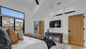 Een moderne slaapkamer met een groot bed, een bureau en een televisie.