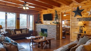 A cozy log cabin interior with a fireplace, wooden furniture, and a star decoration on the wall.
