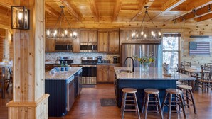 A spacious kitchen with wooden cabinets, stainless steel appliances, and a central island with stools.