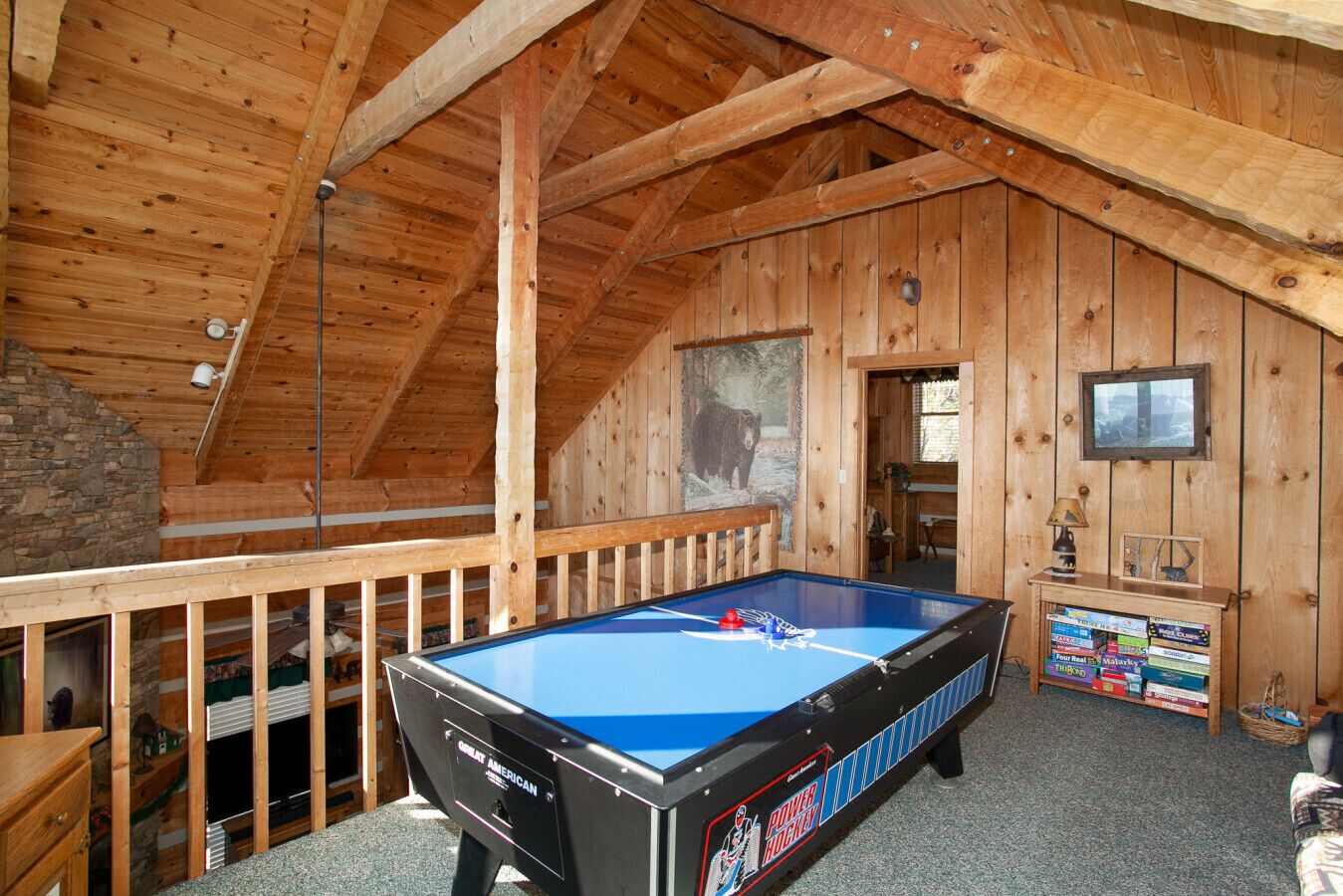 Une pièce chaleureuse au décor rustique, avec une table de billard, un mur en pierre et un tableau représentant un ours.