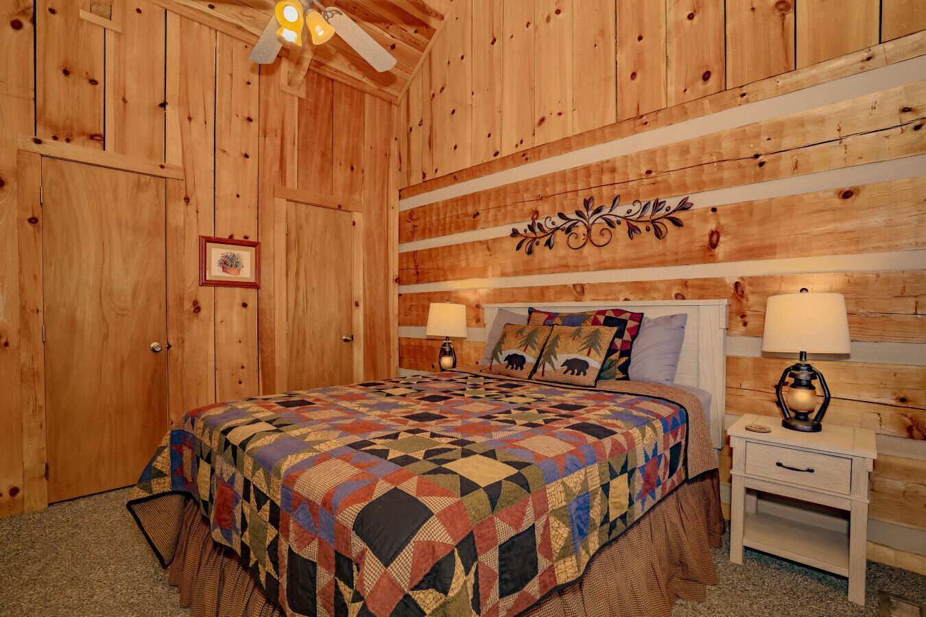 A wooden room with a bed, two bedside tables, a ceiling fan, and a wall-mounted decoration.