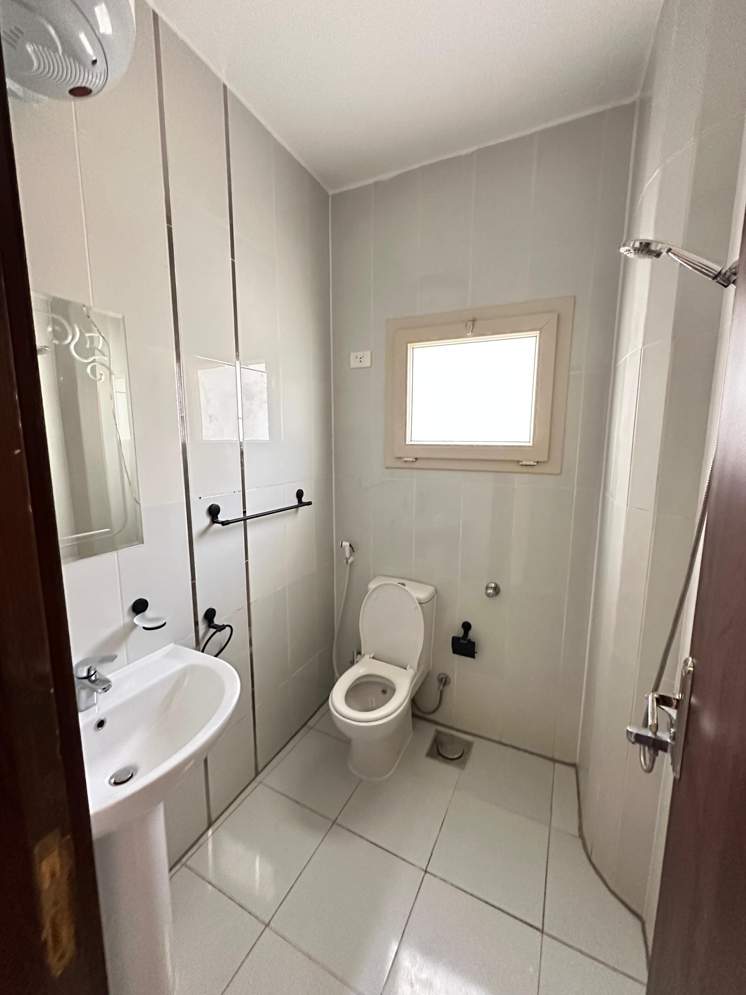 Un baño pequeño y limpio, con inodoro, lavamanos y ventana.
