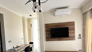 Una sala de estar moderna con comedor, televisor montado y mueble empotrado para entretenimiento.