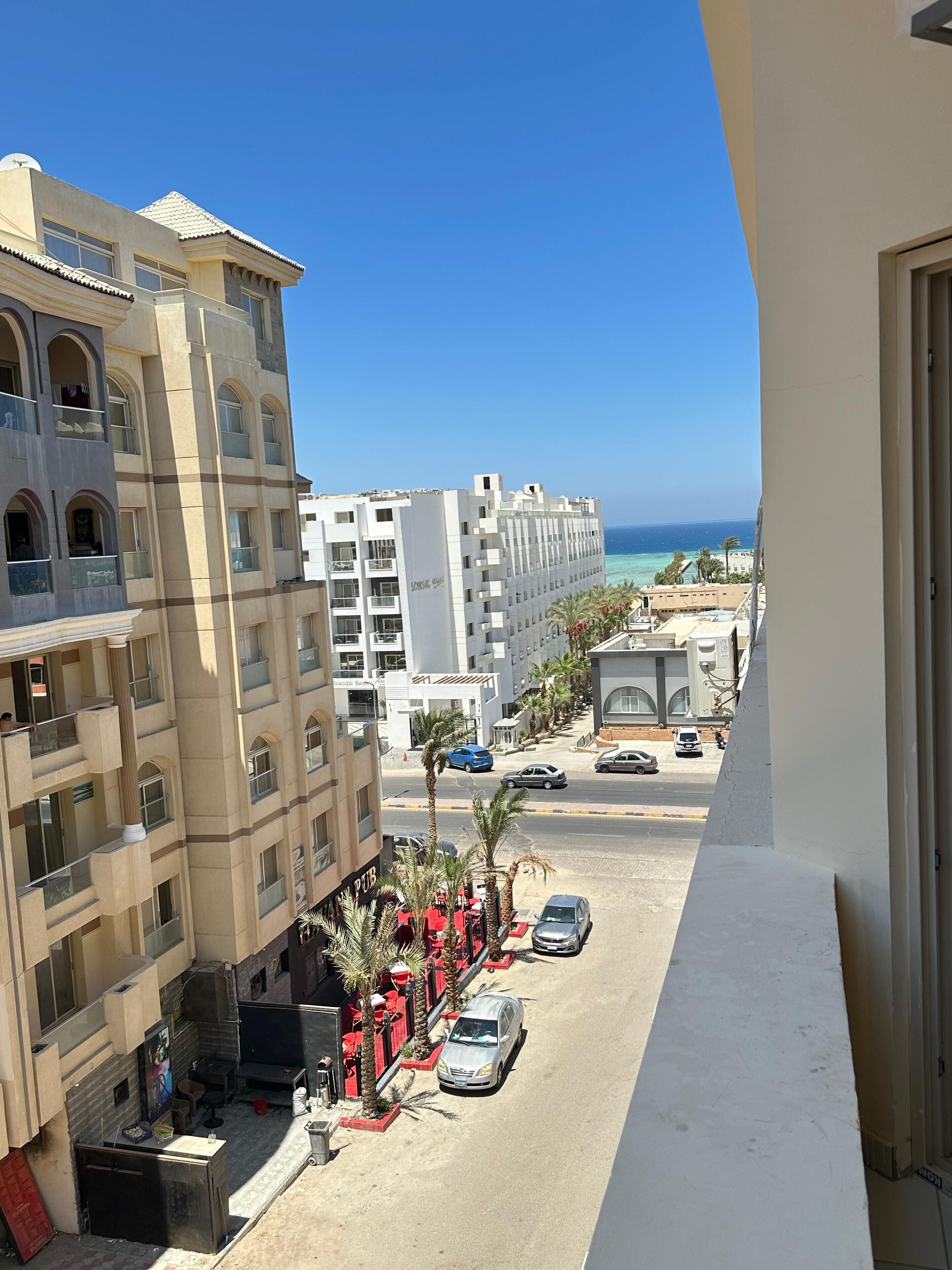 Un hotel de varios pisos con balcones que dan a una calle y una playa.
