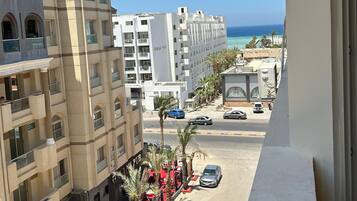 Un hotel de varios pisos con balcones que dan a una calle y una playa.