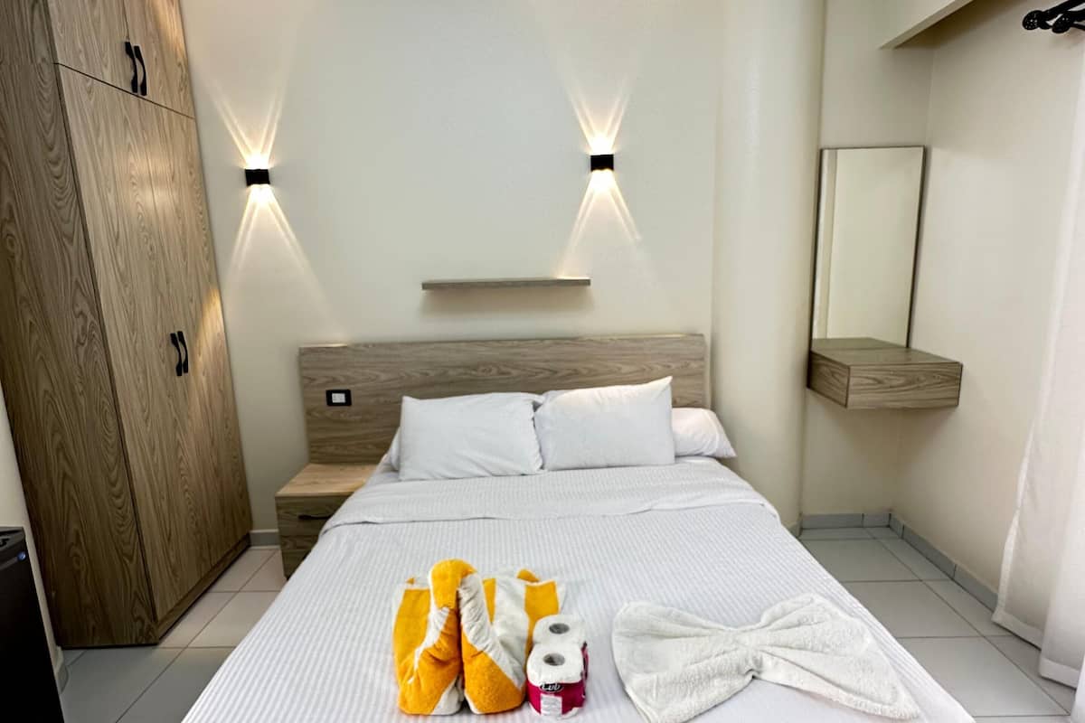 Quarto moderno com cama grande, guarda-roupa de madeira e iluminação embutida.