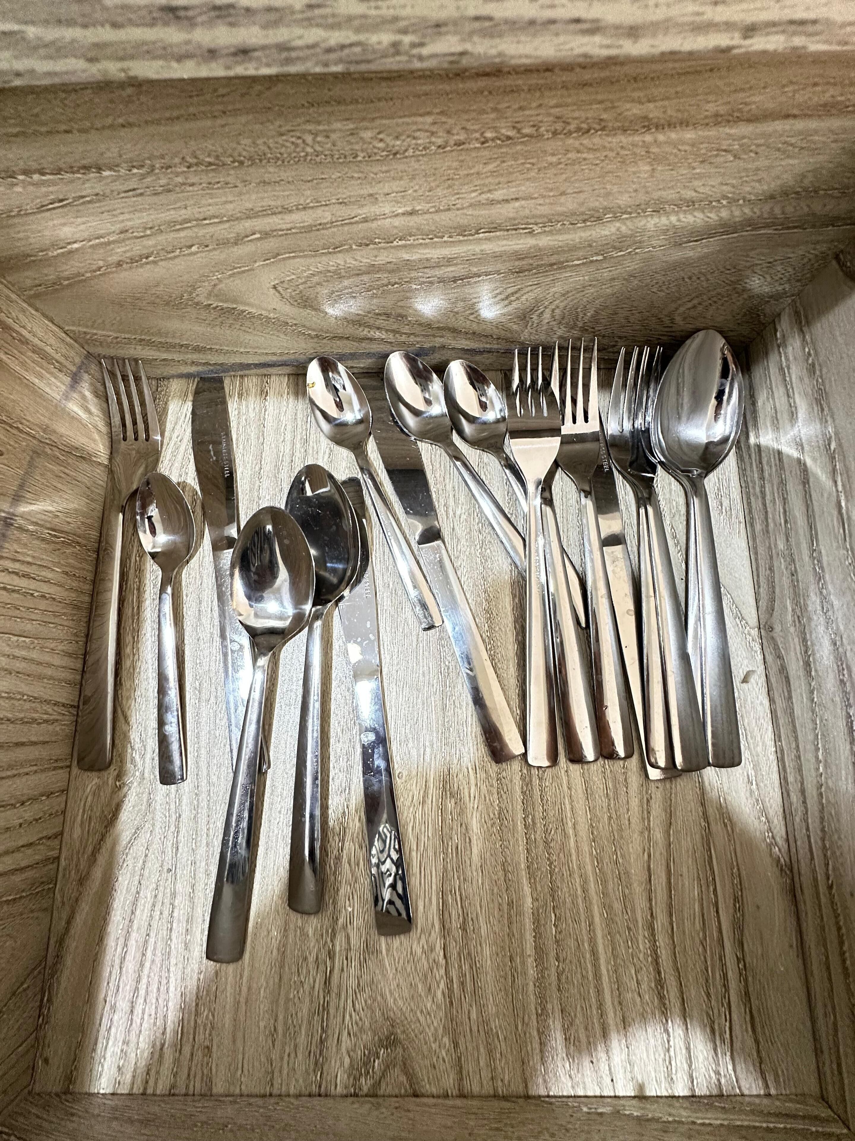 Eine Holzkassette mit verschiedenen Besteckstücken, darunter Gabeln, Löffel und Messer.