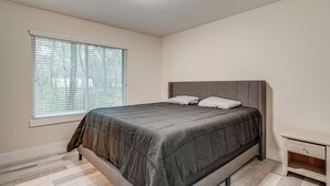 A bedroom with a bed, a nightstand, and a window with blinds. - Family Retreat w/ Pool Table Near the Woodlands! (Spring)