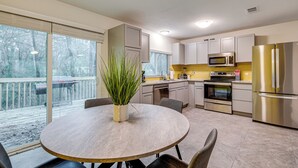 A modern kitchen with a dining area, large windows, and a view of a deck. - Family Retreat w/ Pool Table Near the Woodlands! (Spring)