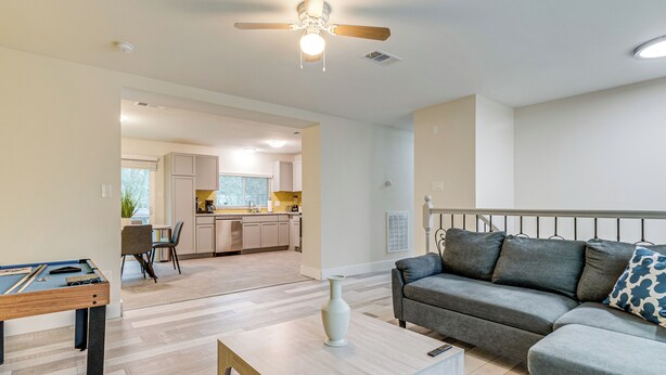 A modern living room with a pool table, a gray sofa, and a ceiling fan. - Family Retreat w/ Pool Table Near the Woodlands! (Spring)