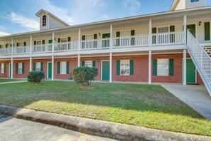 Classic two-story motel with a flat roof and symmetrical facade, featuring balconies with white railings and green shutters.