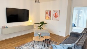 Una sala moderna con una televisión de pantalla plana, un conjunto de sofás, una mesa de centro y una alfombra estampada.
