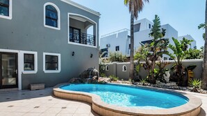Ein Pool mit geschwungener Kante, umgeben von einer gefliesten Terrasse.