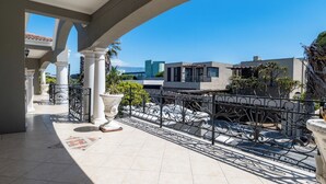 Ein geräumiger Balkon mit Fliesenboden, weißen Säulen und schmiedeeisernen Geländern.