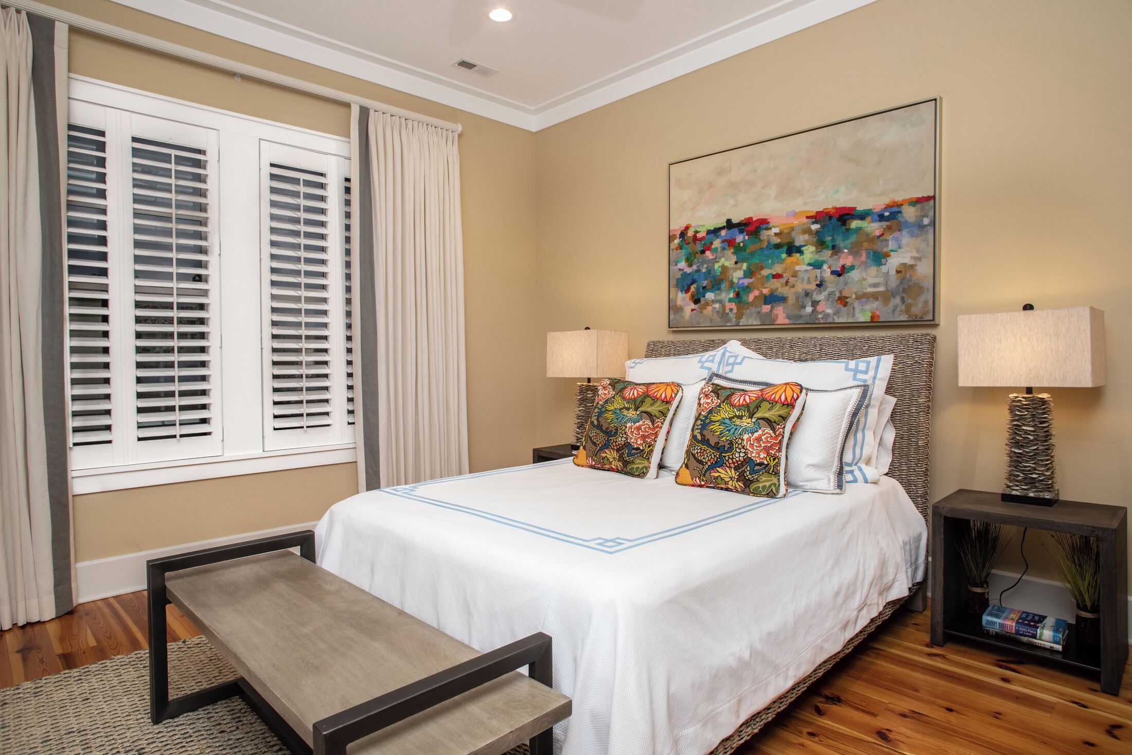 A neatly arranged bedroom with a bed, bedside tables, and a bench.