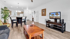 A spacious living room with a wooden coffee table, a TV on a wooden stand, and a ceiling fan. - Myrtlewood 2-bedroom condo.  Pool in the backyard (Myrtle Beach)