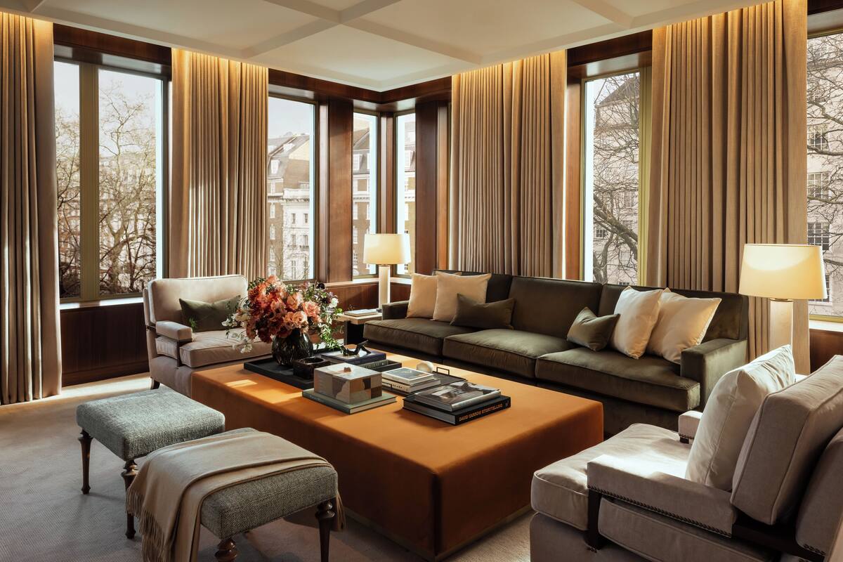 A modern hotel room with a large window, a sofa, a coffee table, and a chair.