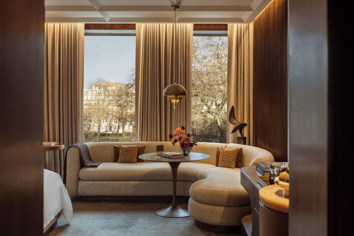 A modern living room with a curved sofa, a round coffee table, and a view of a cityscape through large windows with curtains.