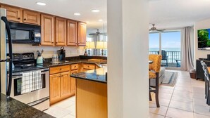 A kitchen with wooden cabinets, a microwave, stove, and a large island.