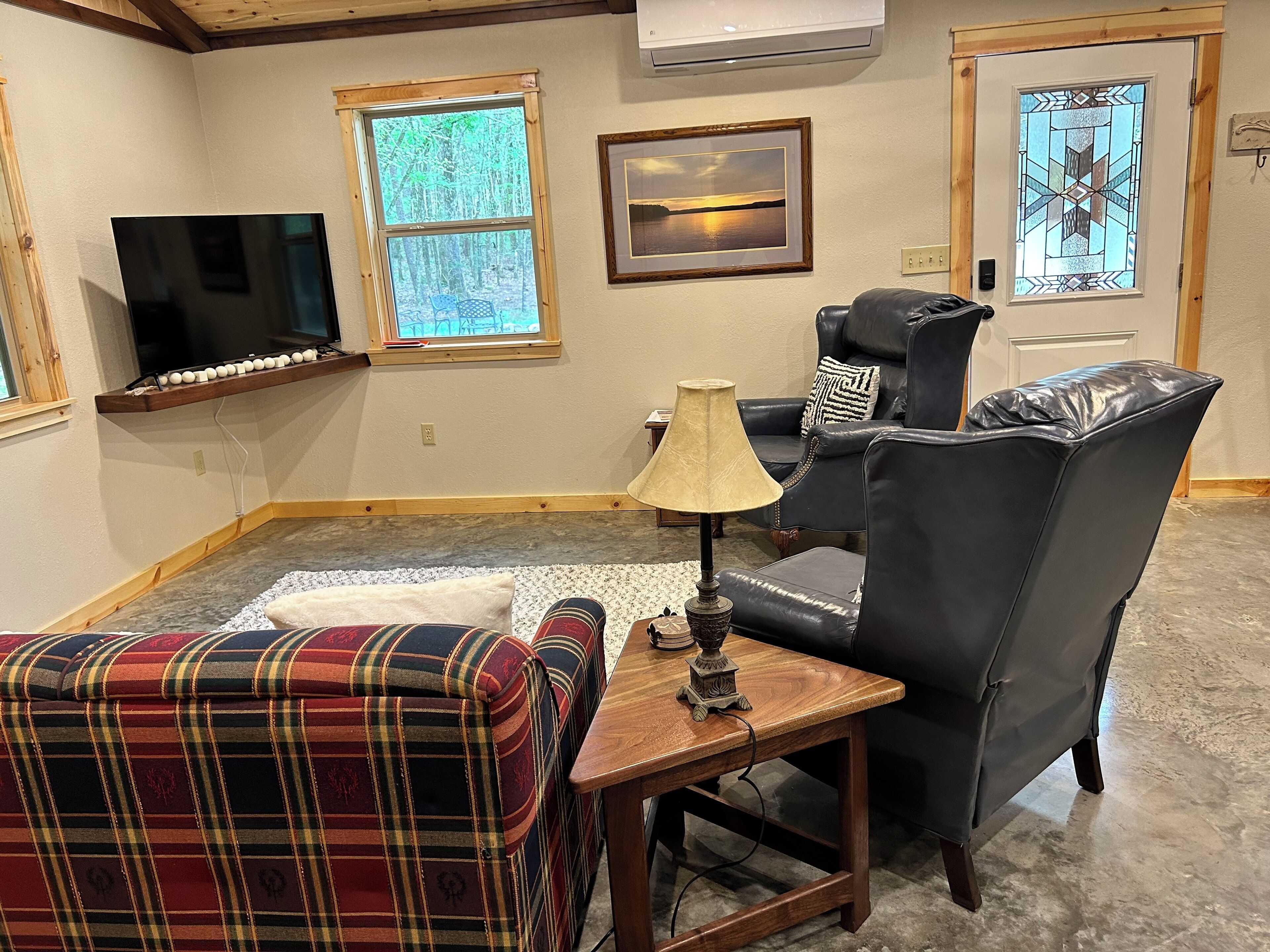 Een woonkamer met een televisie, een open haard, een groot raam en een deur met een glas-in-lood ontwerp.