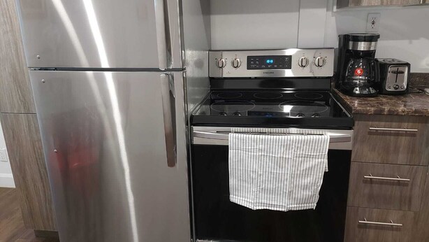 Et køkken med et rustfrit stål køleskab, en Samsung gas komfur og en kaffemaskine.