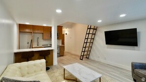 A modern apartment with a kitchen, living room, and a TV mounted on the wall.