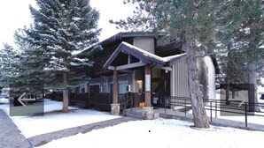A lodge with a covered entrance, stone pillars, and a snow-covered ground.