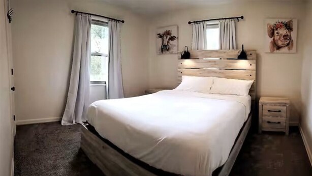 Camera da letto con una testiera in legno, un letto singolo, un comodino e una finestra con tende.