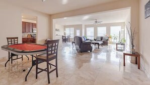 A spacious living area with a pool table, comfortable seating, and a kitchen in the background. - Spacious 4-Bedroom Getaway for Families & Groups (Katy)