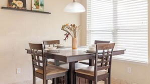 A dining area with a wooden table and chairs, a vase with dried flowers, and a hanging light fixture. - Spacious 4-Bedroom Getaway for Families & Groups (Katy)