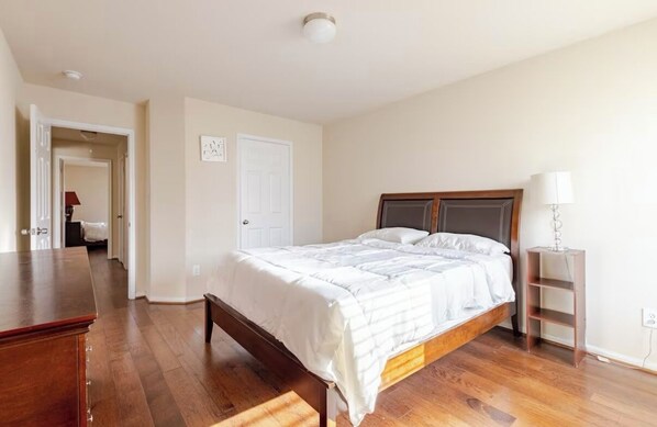 A bedroom with a wooden bed, a bedside table, and a nightstand.