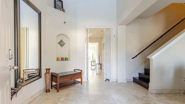 A spacious hallway with a wooden bench, a large mirror, and a staircase leading to another level. - Spacious 4-Bedroom Getaway for Families & Groups (Katy)